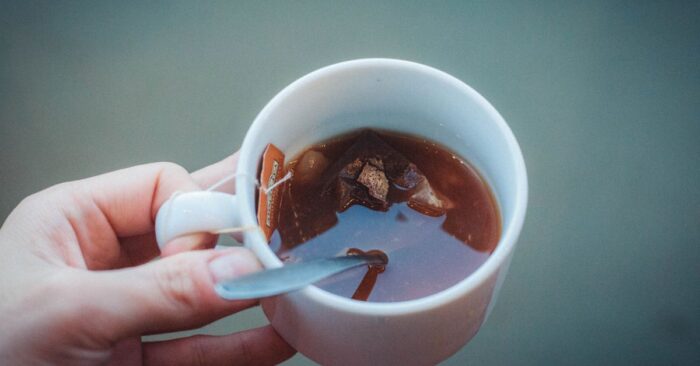 シンプルな白いカップにティーバッグ紅茶を注ぐ瞬間。やわらかな光が差し込むキッチンの雰囲気。