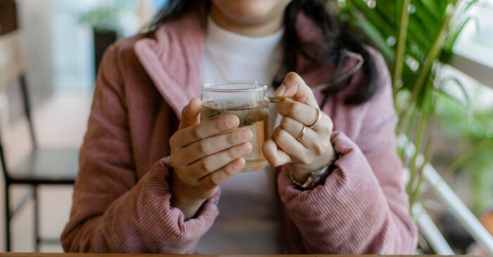 紅茶の湯気を見つめながら深呼吸する女性。穏やかな表情で心を整えている様子。