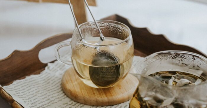 寝る前にカフェインレス紅茶を飲むママの様子。ベッドサイドで湯気の立つティーカップを持ち、穏やかな笑みを浮かべている。