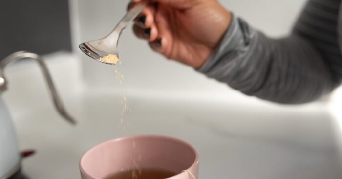 紅茶の香りを深く吸い込みながら微笑む女性。柔らかな午後の光が差し込むリビングの雰囲気。