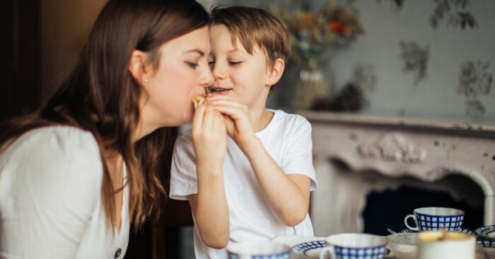 夜、カフェインレス紅茶を飲みながら穏やかに微笑むママ。湯気の立つカップと柔らかい光が癒しの雰囲気を演出している。