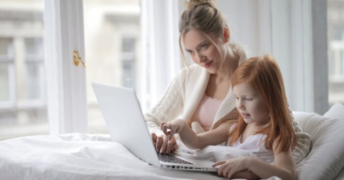 寝る前にカフェインレス紅茶を飲むママの様子。ベッドサイドで湯気の立つティーカップを持ち、穏やかな笑みを浮かべている。
