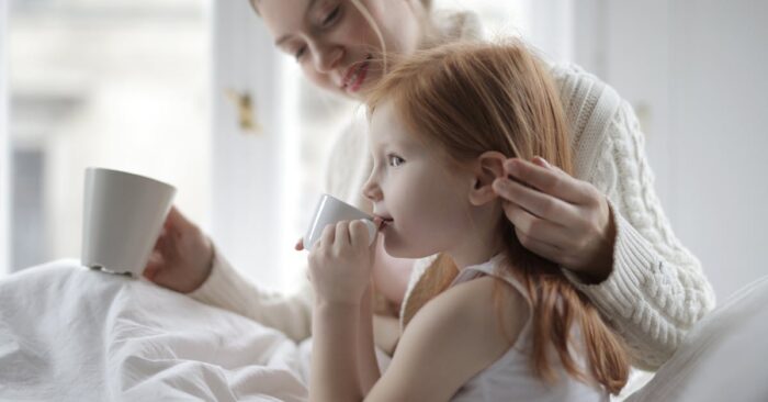 夜、カフェインレス紅茶を飲みながら穏やかに微笑むママ。湯気の立つカップと柔らかい光が癒しの雰囲気を演出している。