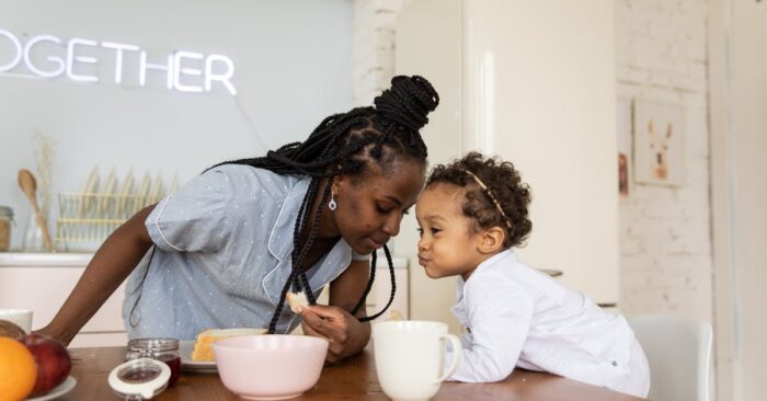 朝の食卓で親子が紅茶を飲みながら笑顔で会話する様子。カフェインレス紅茶を通じて穏やかな時間を共有するイメージ。