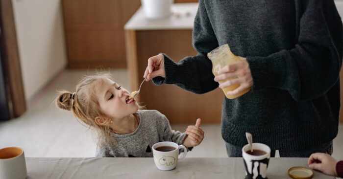 朝の食卓で親子が紅茶を飲みながら穏やかに過ごす様子。子どもと一緒にティータイムを楽しむ家庭の風景を表現した画像。