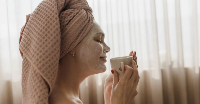 紅茶の香りを深く吸い込みながら微笑む女性。柔らかな午後の光が差し込むリビングの雰囲気。