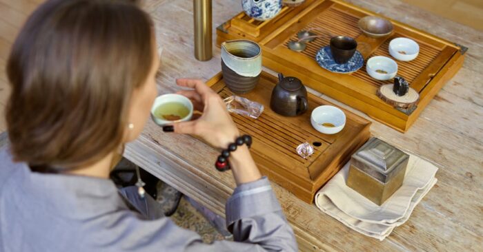 紅茶の香りを深く吸い込みながら微笑む女性。柔らかな午後の光が差し込むリビングの雰囲気。