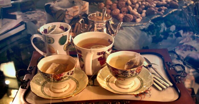 シンプルな白いカップにティーバッグ紅茶を注ぐ瞬間。やわらかな光が差し込むキッチンの雰囲気。