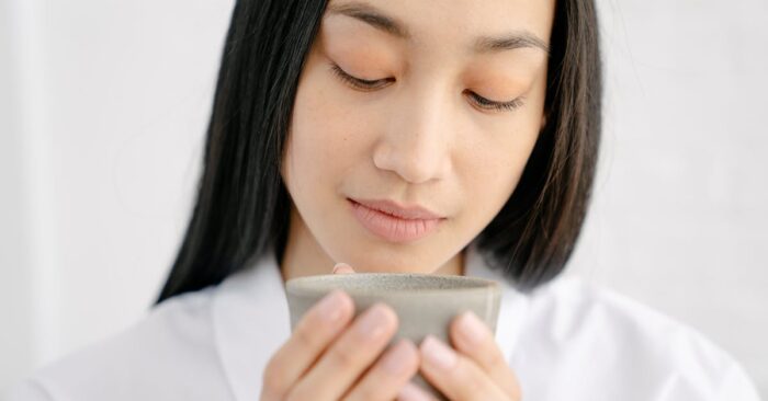 紅茶の香りを感じながら深呼吸する穏やかな女性と温かな雰囲気