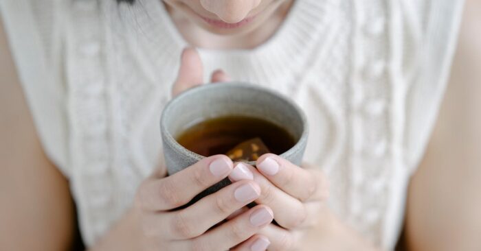 紅茶を飲みながら穏やかな時間を過ごす女性の手元と柔らかな光の風景