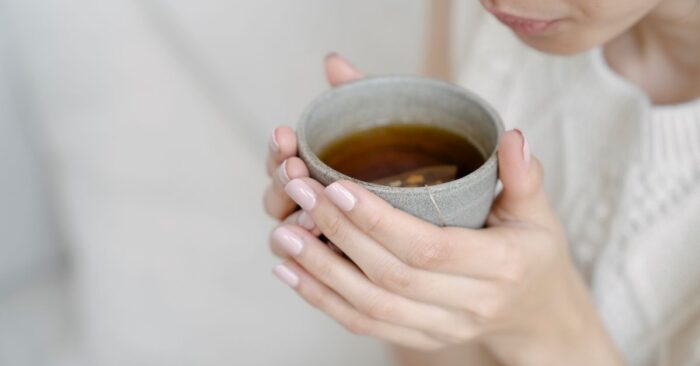 紅茶の湯気を見つめながら深呼吸する女性。穏やかな表情で心を整えている様子。