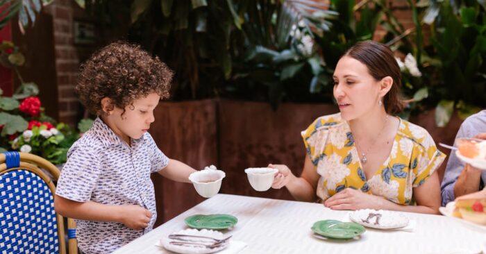 寝る前にカフェインレス紅茶を飲むママの様子。ベッドサイドで湯気の立つティーカップを持ち、穏やかな笑みを浮かべている。
