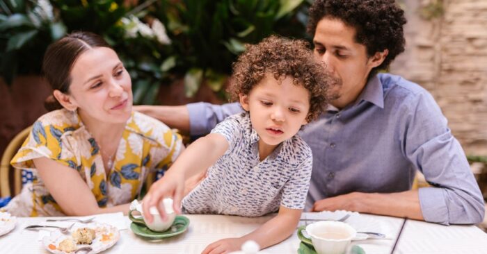 朝の食卓で親子が紅茶を飲みながら笑顔で会話する様子。カフェインレス紅茶を通じて穏やかな時間を共有するイメージ。
