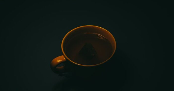 シンプルな白いカップにティーバッグ紅茶を注ぐ瞬間。やわらかな光が差し込むキッチンの雰囲気。