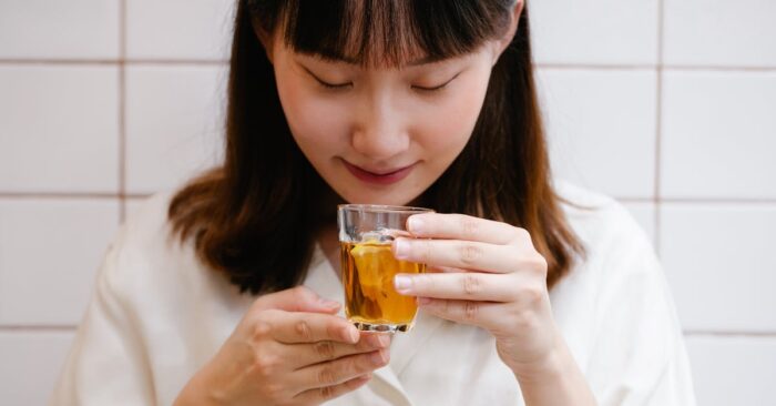 紅茶の香りを深く吸い込みながら微笑む女性。柔らかな午後の光が差し込むリビングの雰囲気。