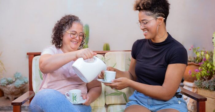 紅茶を手に優しく微笑むママ。窓辺のやわらかな光が差し込み、穏やかな幸福感に包まれている様子。