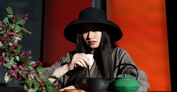紅茶の香りを深く吸い込みながら微笑む女性。柔らかな午後の光が差し込むリビングの雰囲気。
